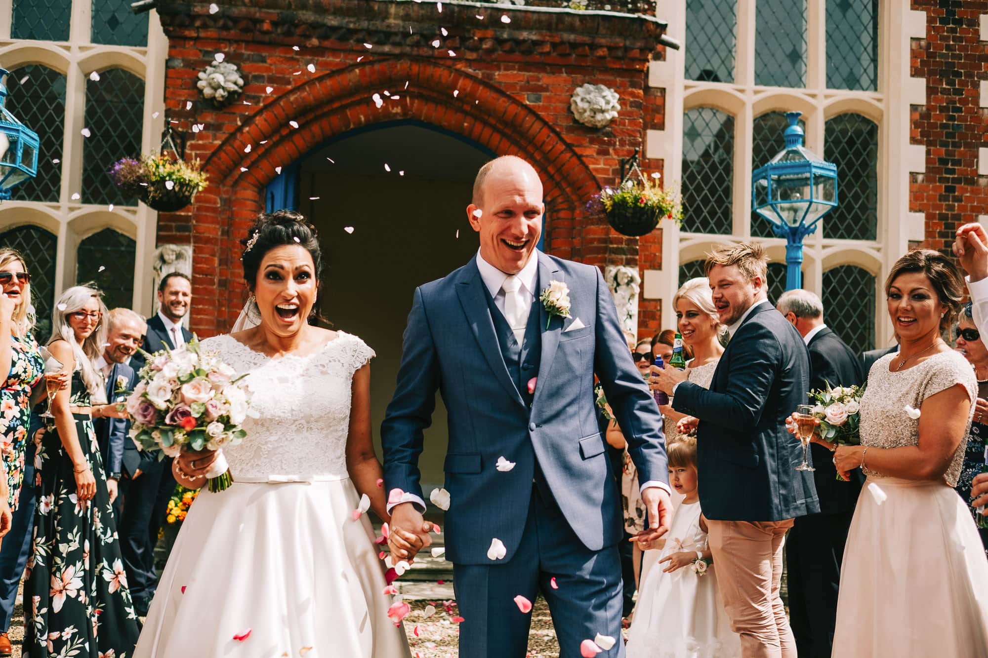 Bride and groom walk down the confetti line at Gosfield Hall