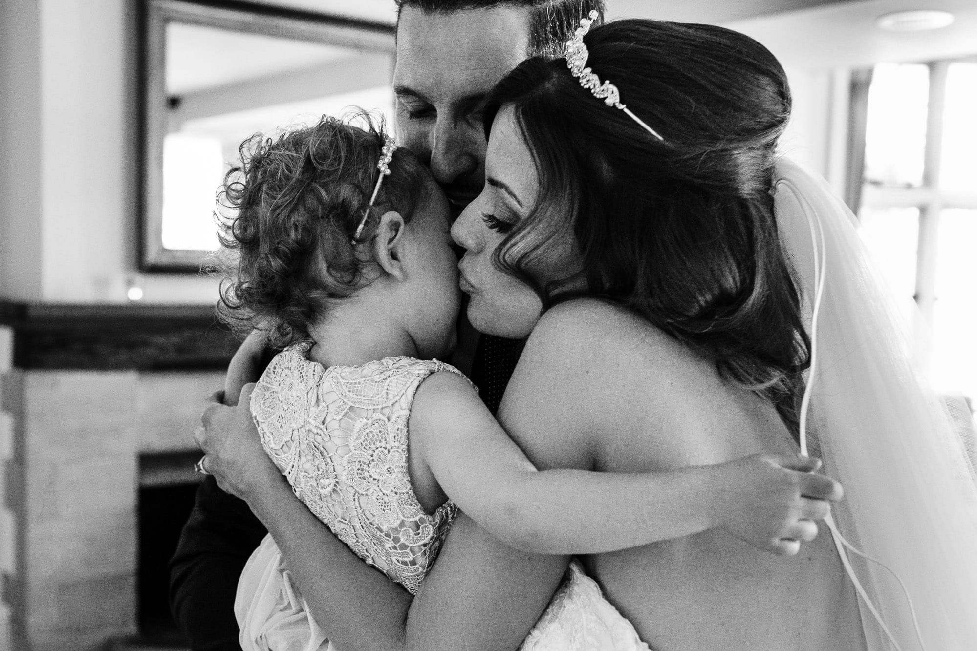 Bride and groom both kiss their daughter