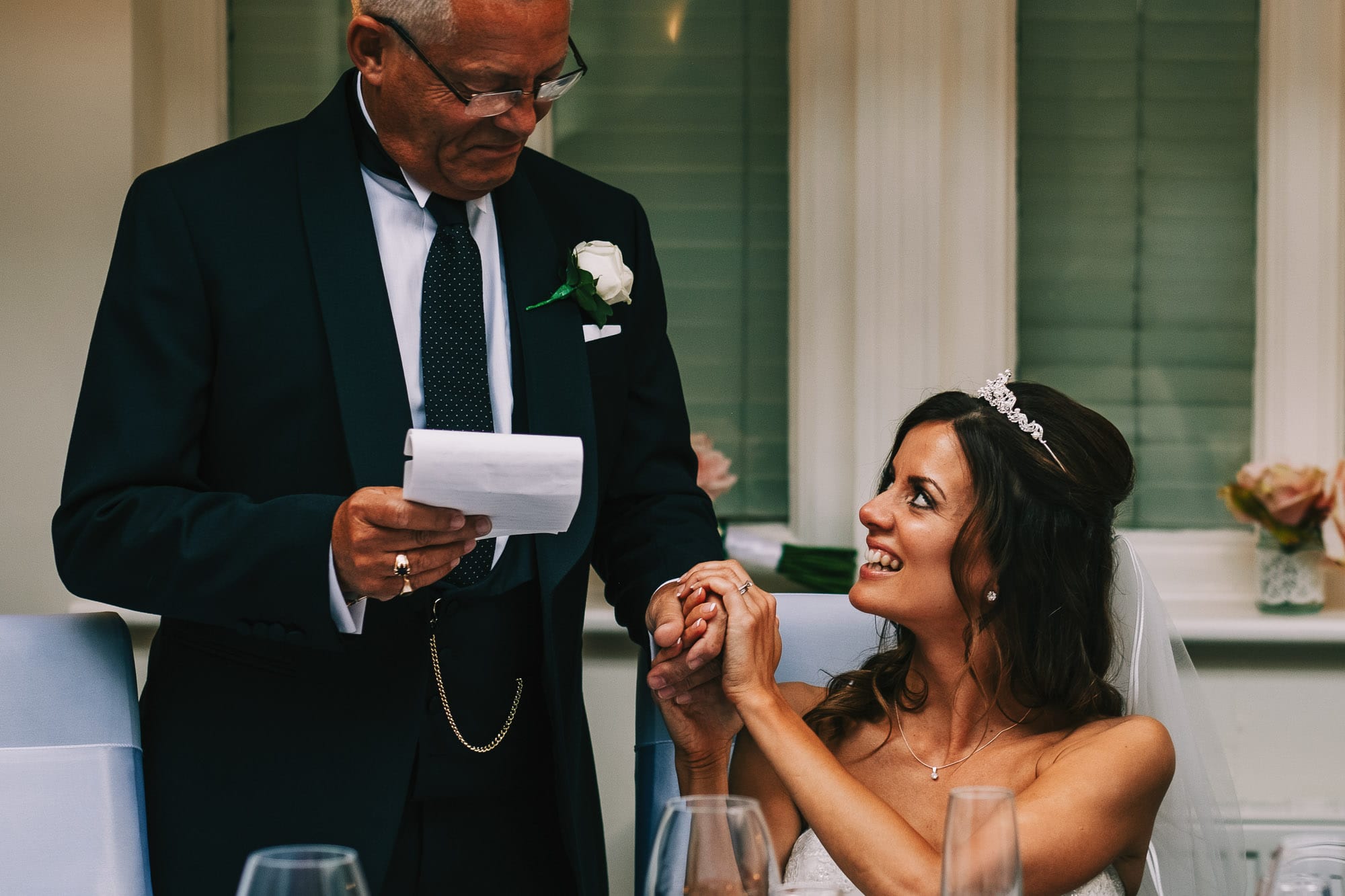 Bride holds her dads hand during his speech