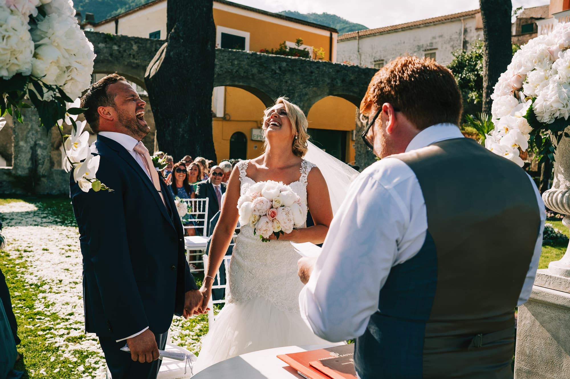 Bride and groom laugh at the reading during the ceremony
