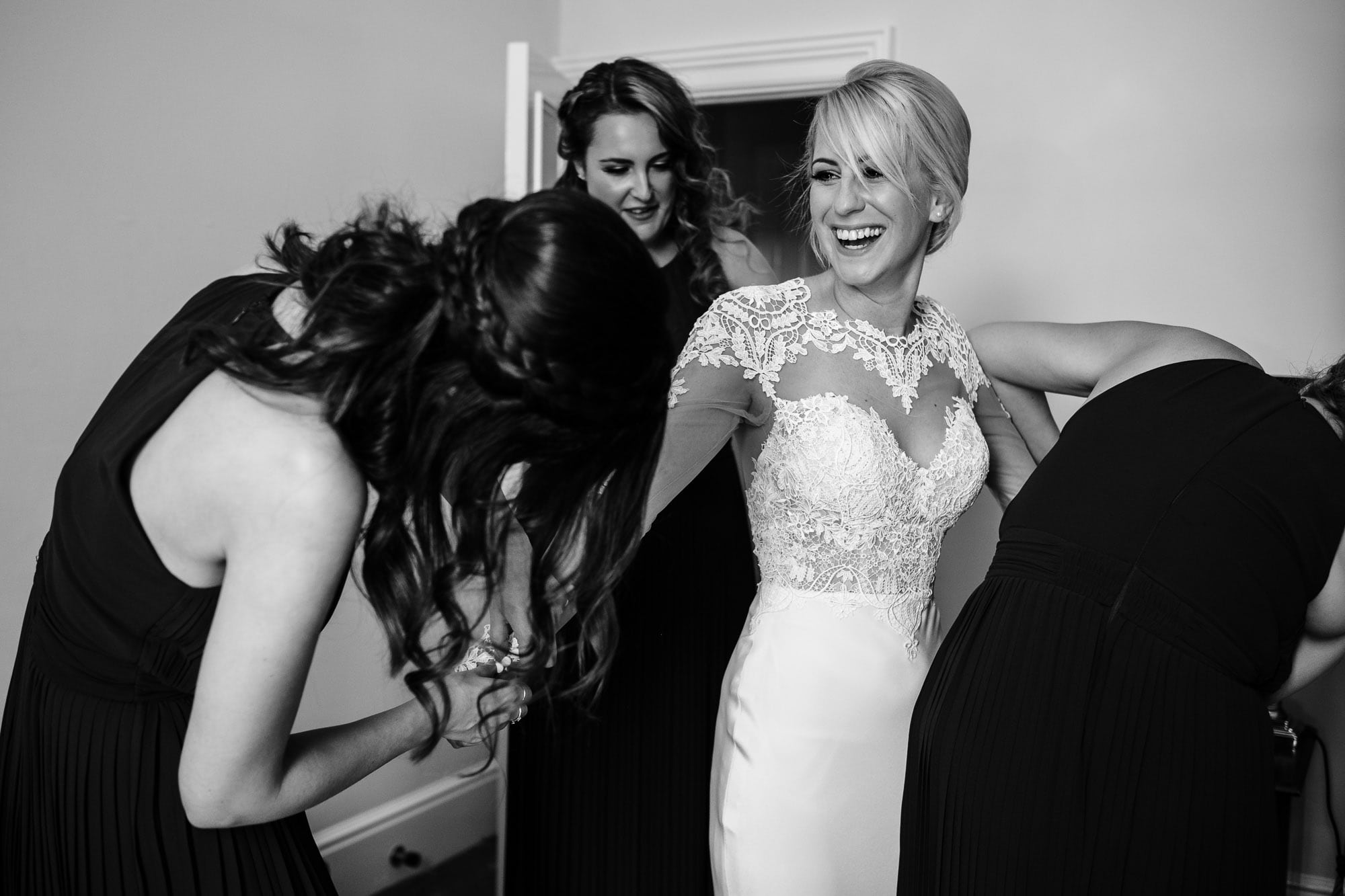 Bridesmaids helping the bride in her dress