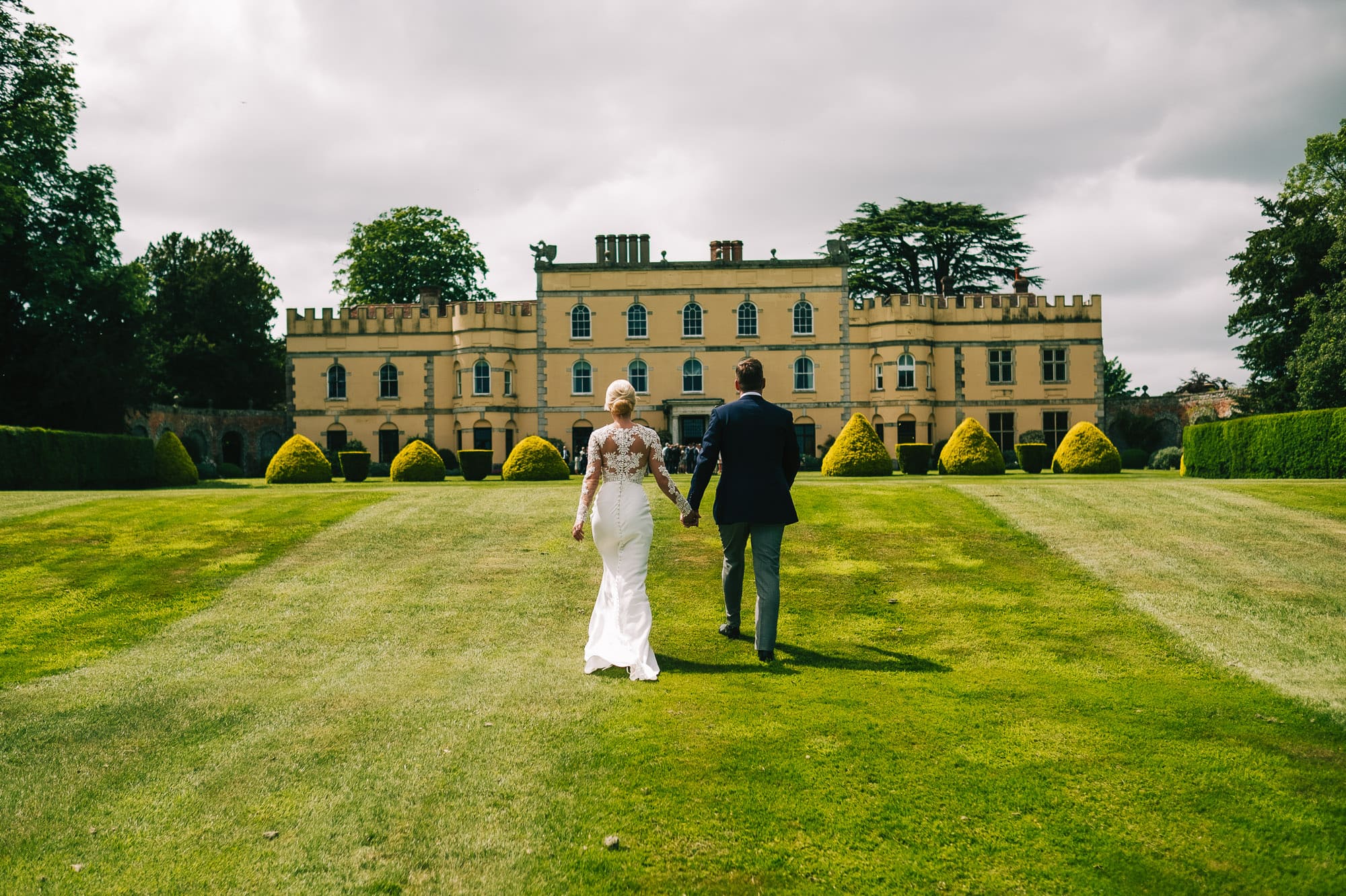 Bride and groom walking down the gardens at Hampden House