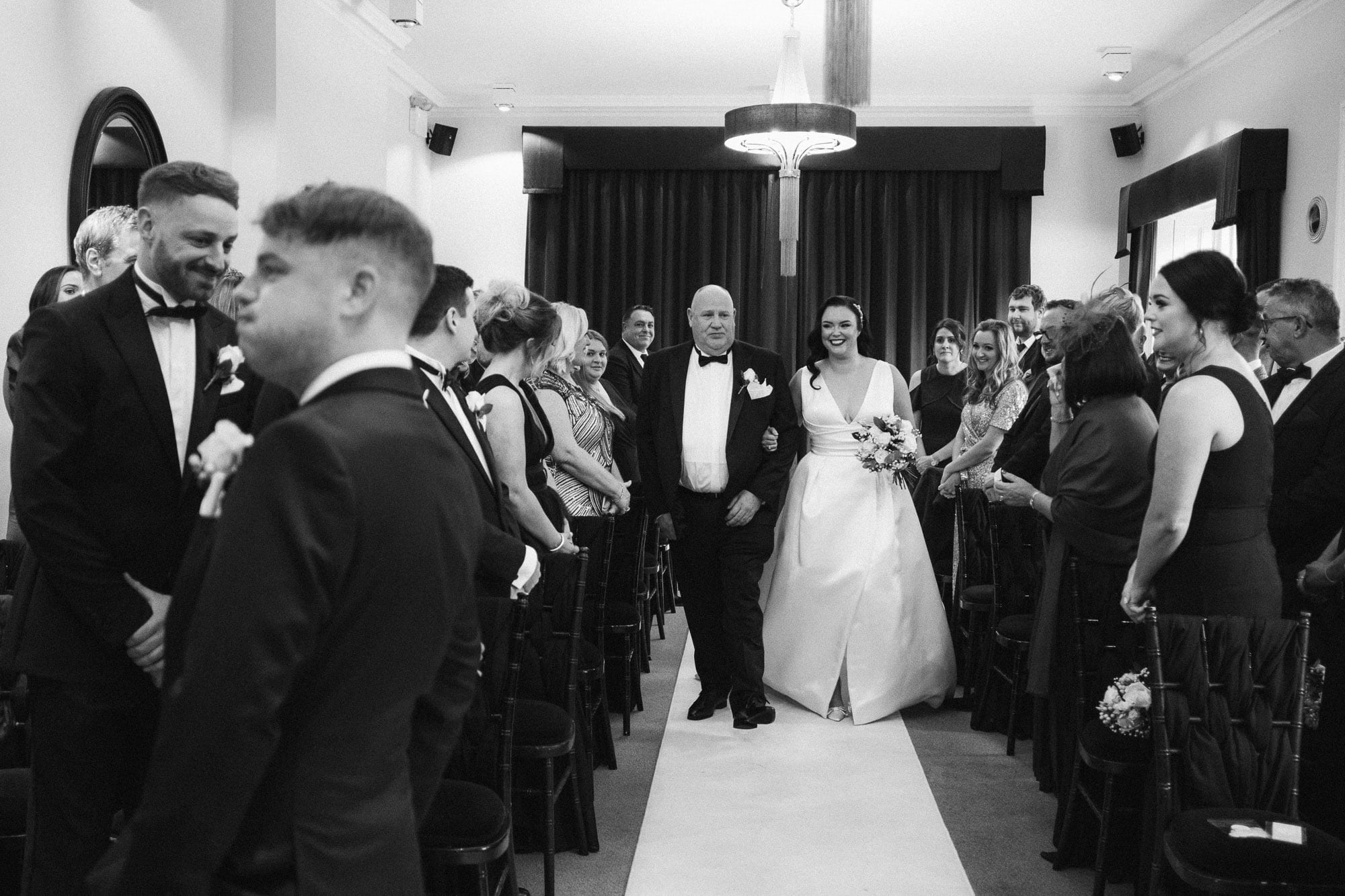 Groom puffs his cheeks as he reacts to his future wife walking up the aisle