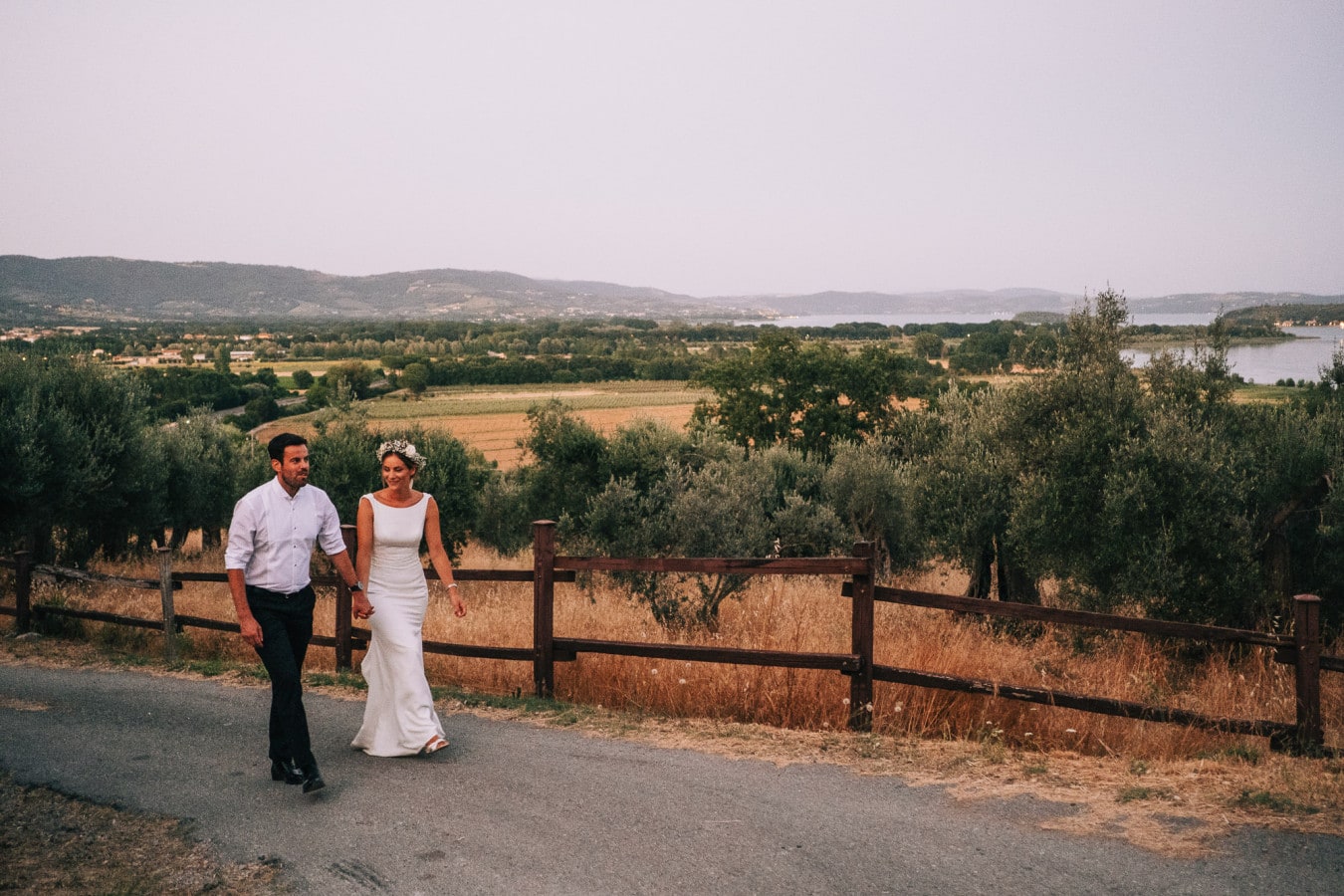 Bride and groom walking up the path at Agriturismo La Dogana with beautiful Tuscan countryside in the background