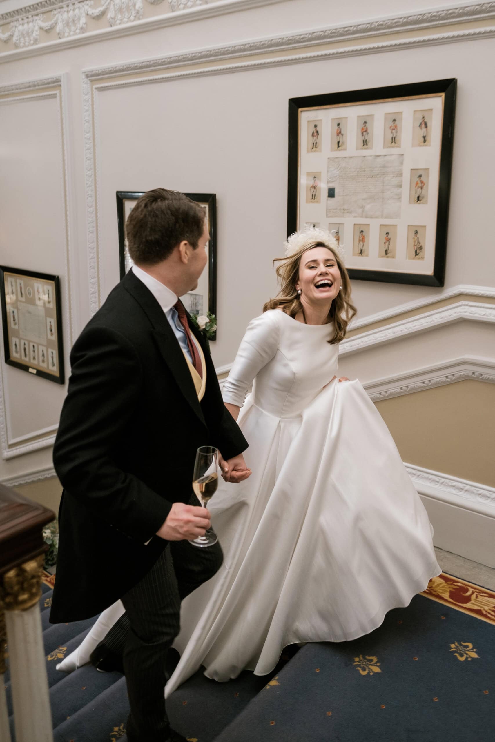 Bride laughing as they walk up the stair to the wedding breakfast